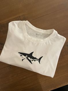 A shark print graphic tee with short sleeves Shark Things, Travel Jewellery Box, Shark Tee, Shark Print, Shark Shirt, Shark T Shirt, Crochet Design Pattern, Leather Bookmark, Vinyl Shirts