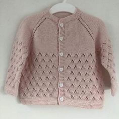 a pink knitted sweater hanging on a clothes hanger next to a white wall