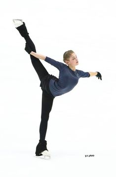 a woman is doing a trick with her leg up in the air while wearing black pants and a blue shirt