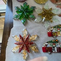 christmas decorations are displayed on a piece of white paper with gold and green sequins