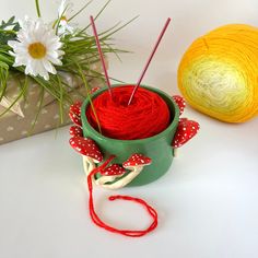 two balls of yarn sitting next to each other in a green container with red and white polka dots