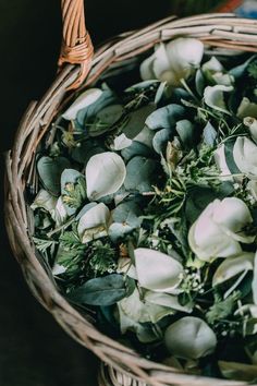 a basket filled with white flowers and greenery