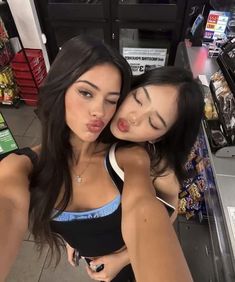 two young women are hugging each other in a grocery store, one has her tongue out