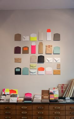 many different types of envelopes are on the wall above a desk with several boxes