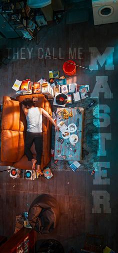 a man standing on top of a couch next to a table filled with books and magazines