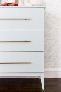 a white dresser with gold handles in a room