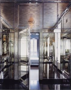 the mirrored doors are open to reveal a room with a bed and chandelier