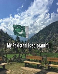 there is a green and white flag flying in the sky over two wooden benches that are facing each other