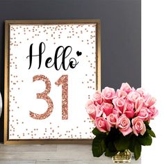 there is a vase with pink roses in it next to a framed sign that says hello 31