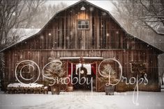 an old barn with christmas trees in front of it and snow falling on the ground