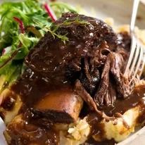 a close up of a plate of food with meat and vegetables on it, next to a fork