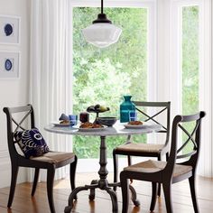 a dining table with two chairs and plates on it in front of a large window