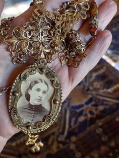 a woman's hand holding an old fashioned necklace with a photo on it,