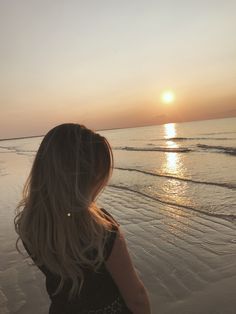 a woman standing on top of a beach next to the ocean