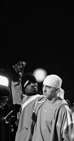 a black and white photo of a man with a towel on his head standing next to another man