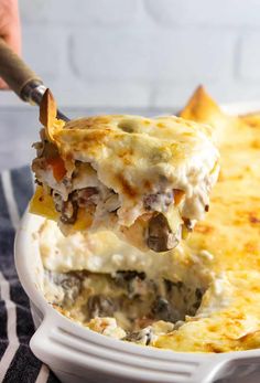 a casserole dish with meat and cheese being lifted from the casserole