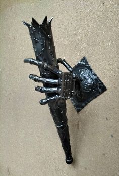 a sculpture of a hand holding a piece of metal on top of a cement ground