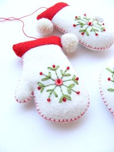 three white mittens with red and green decorations