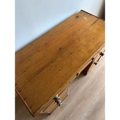 an old wooden desk sitting on top of a hard wood floor next to a wall