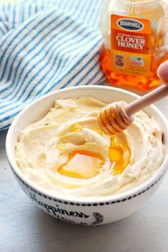 a hand holding a honey dip in a bowl