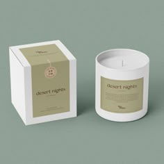 a white candle sitting next to a box on top of a green surface with the words desert nights printed on it