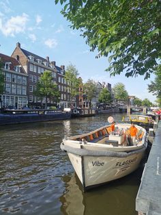 a boat that is sitting in the water next to some buildings and trees on either side of it