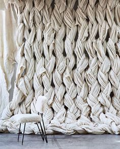 a chair sitting in front of a wall made out of cloth