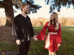 a man and woman holding hands in front of a tree