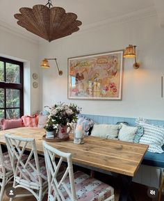 a wooden table sitting under a window next to a blue bench with flowers on it