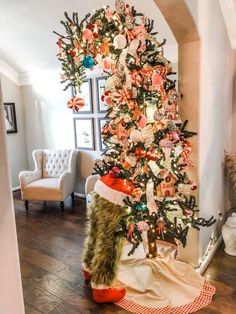 a decorated christmas tree in the corner of a living room with an orange and white theme