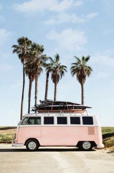 an old vw bus with surfboards on top parked in front of palm trees