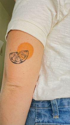 a person with a tattoo on their arm and an orange slice in the shape of a heart