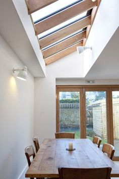 a wooden table sitting under a skylight in a room