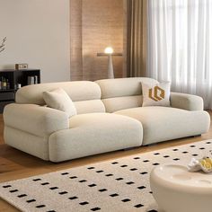 a living room with a white couch and rugs on the wooden floor next to a window