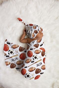 a baby laying on top of a white rug wearing a basketball hat and bib