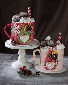 two decorated mugs sitting next to each other on top of a white cake stand