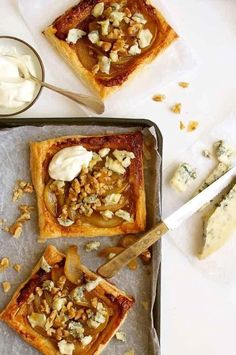 some food that is sitting on top of a baking sheet and next to a bowl of yogurt