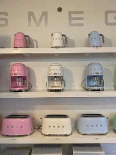 toasters are lined up on shelves with the word smeg written in white above them