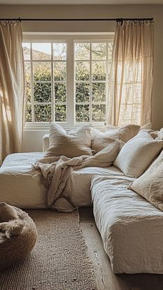 a living room filled with lots of furniture and pillows on top of a rug next to a window