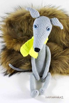 a crocheted rat with a yellow piece in it's mouth