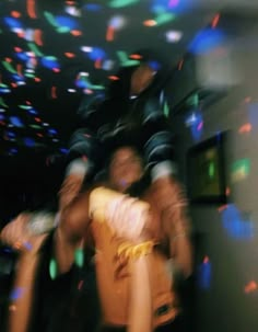 blurry photograph of people dancing in a dance hall with colored lights on the ceiling