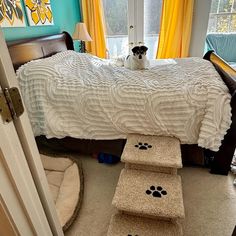 a black and white dog sitting on top of a bed in a room with yellow curtains