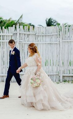 a bride and groom walking together in front of a white picket fence