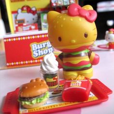 a hello kitty toy is sitting on a tray next to a burger and cupcake