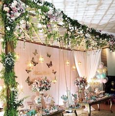 a table covered in lots of flowers next to a wall with butterfly decorations on it