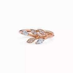 a rose gold ring with three pear shaped diamonds on the top and two leaves on the bottom