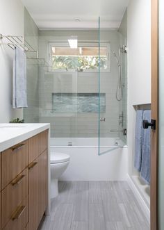 a bathroom with a toilet, sink and bathtub next to a window in the wall