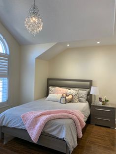 a bedroom with a bed, nightstands and a chandelier hanging from the ceiling