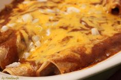 an enchilada with cheese and onions in a white dish