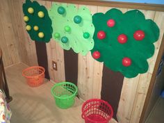 three buckets are lined up in front of a wall decorated with trees and balls